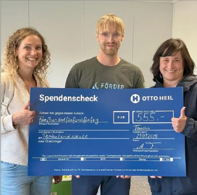 Drei Personen halten einen Spendencheck in die Kamera